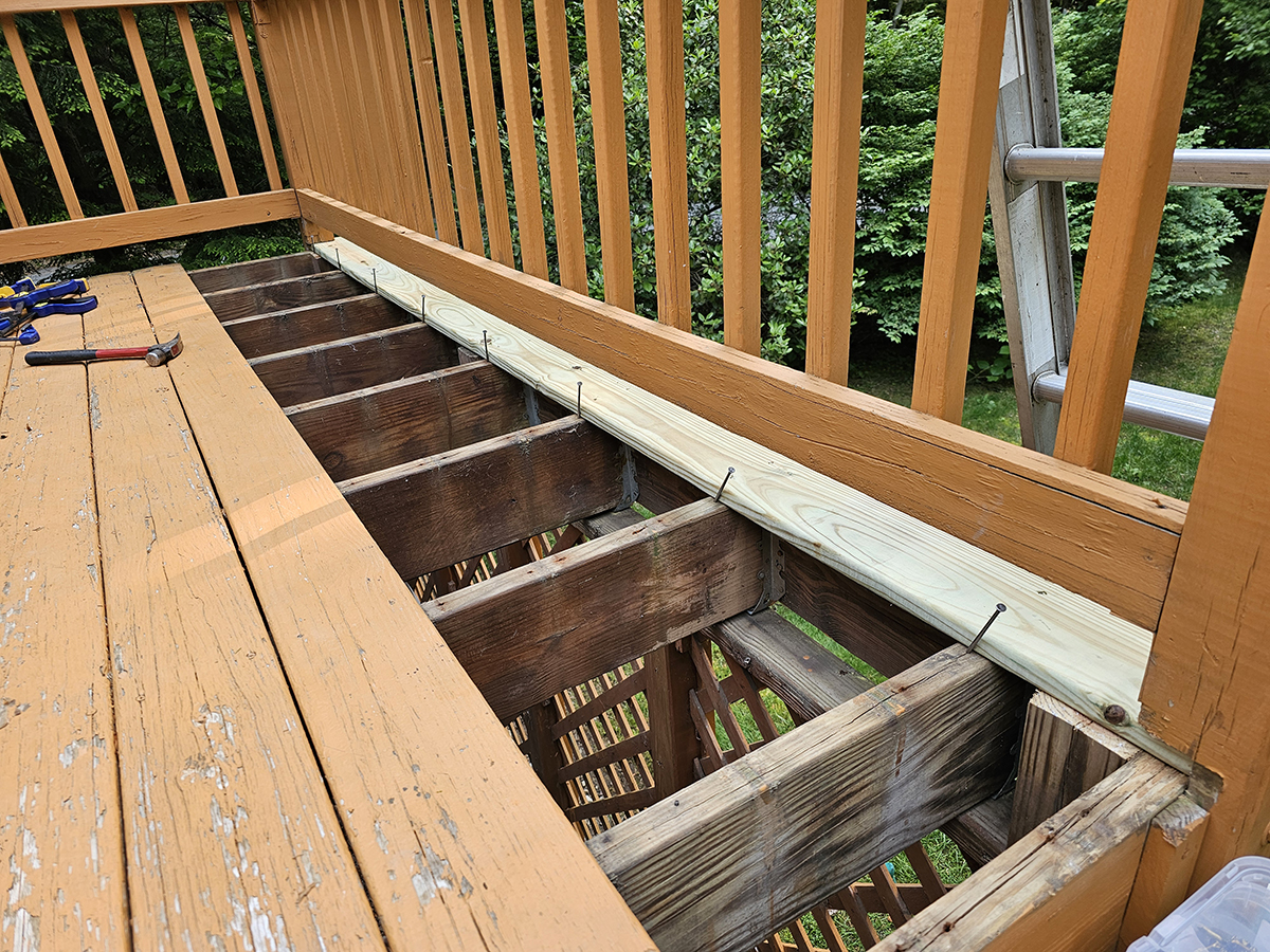 First replacement deck board installed with overhang